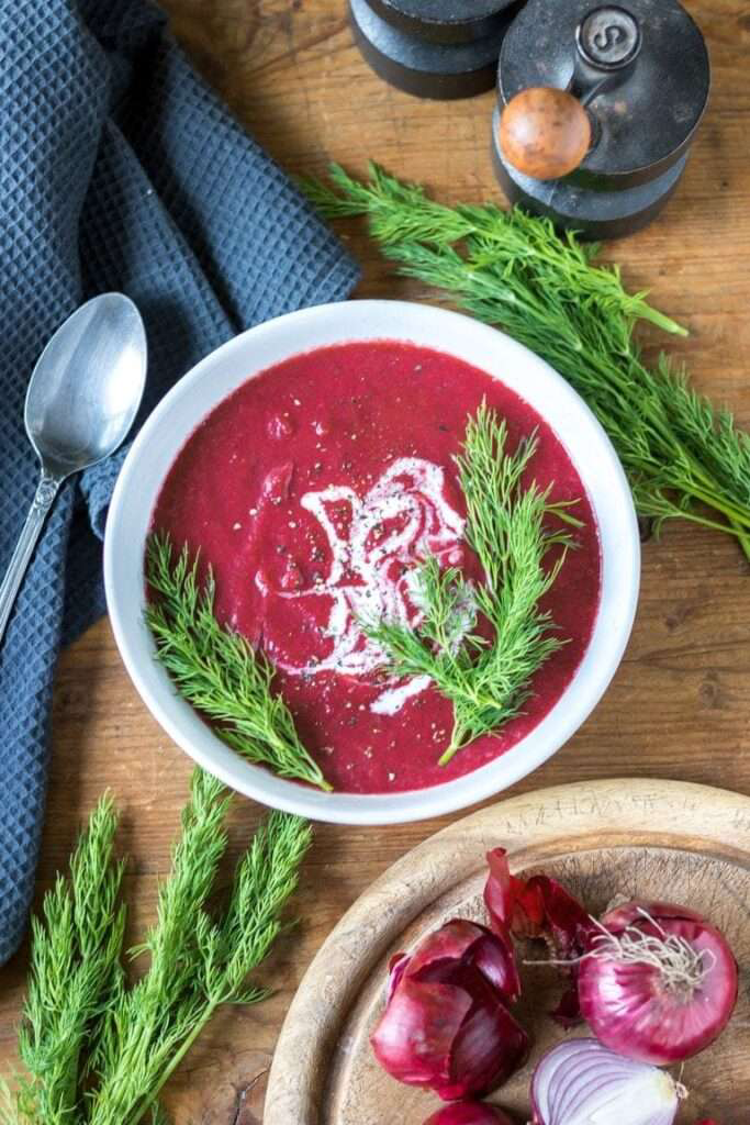 Gotowa zupa krem z buraków podana na głębokim talerzu z dodatkiem koperku. Zdjęcie przez: https://veggiedesserts.com/beetroot-soup/