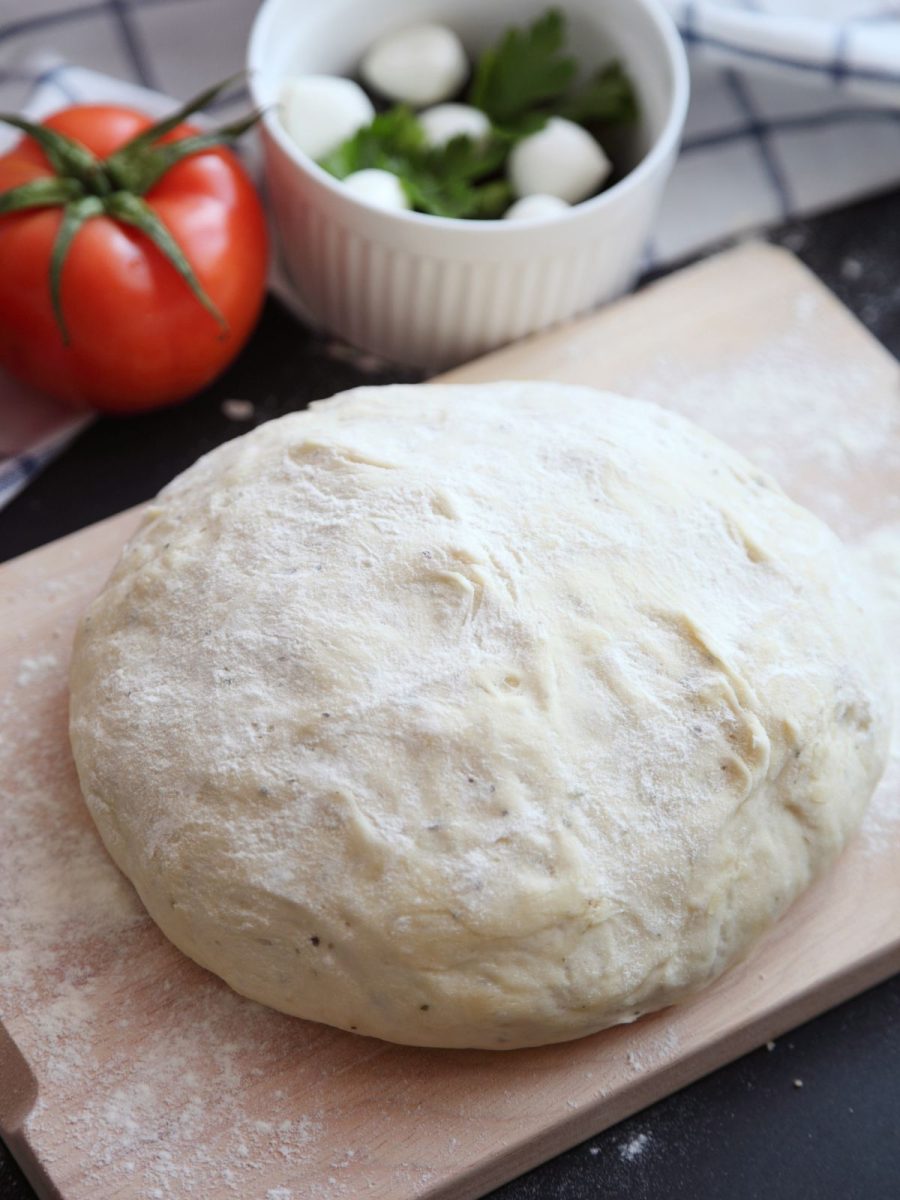 Gotowe ciasto na pizzę na desce do krojenia.